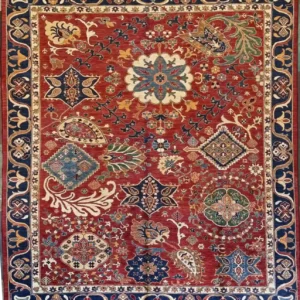 Rust red hand-knotted Chobi wool area rug 8.3' x 10' with scattered ivory medallions and a deep royal blue floral border.