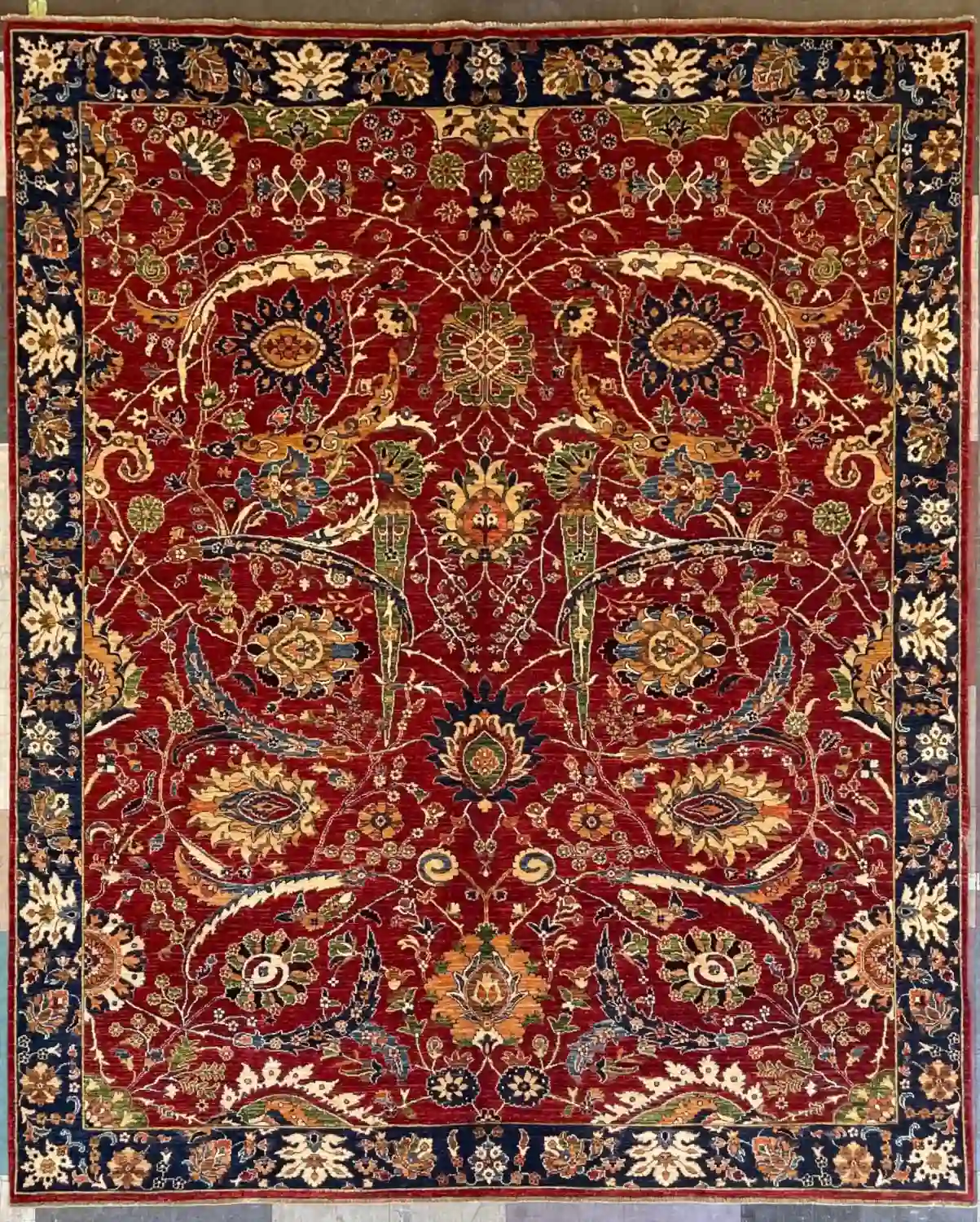 hand-knotted-chobi-wool-area-rug-8-2-x-9-7-ruby-red-midnight-navy-sku-112525-13.webp | McFarlands Carpet and Rug Service Ruby red hand-knotted Chobi wool area rug 8.2' x 9.7' with a symmetrical floral pattern and a dark midnight navy blue border.
