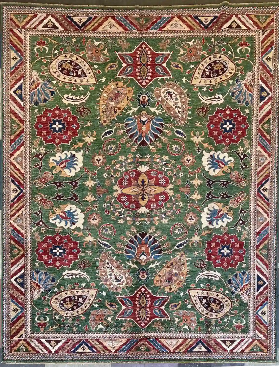 hand-knotted-chobi-peshawar-wool-area-rug-8-4-x-10-2-forest-green-paisley-sku-112525-16.webp | McFarlands Carpet and Rug Service Forest green hand-knotted Peshawar Chobi wool area rug 8.4' x 10.2' featuring red star medallions, large paisleys, and a multicolored chevron border.