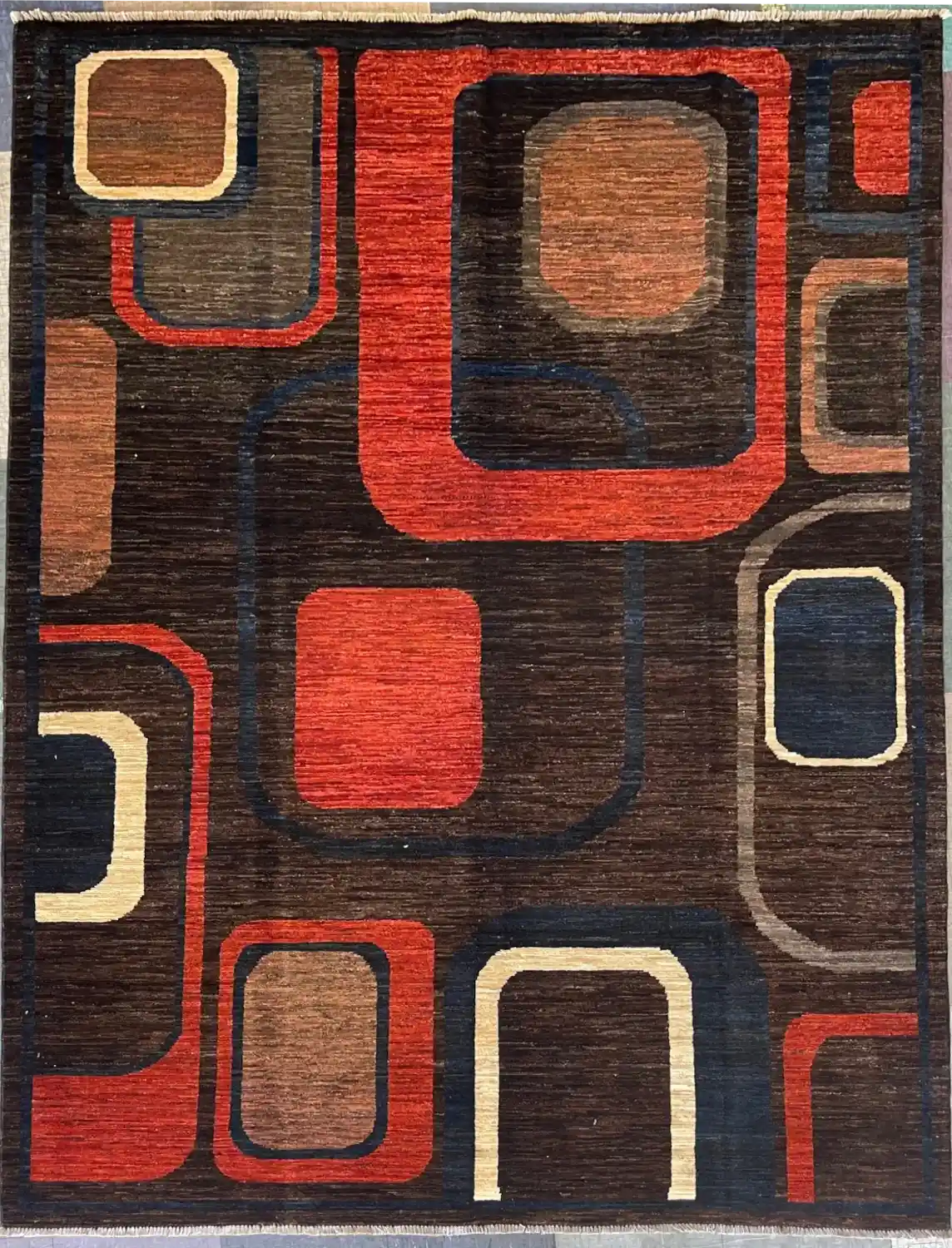 hand-knotted-modern-chobi-wool-area-rug-5-10-x-7-10-abstract-retro-cubes-sku-112525-18.webp | McFarlands Carpet and Rug Service Dark brown hand-knotted Modern Chobi wool area rug 5.10' x 7.10' featuring an abstract geometric pattern of overlapping rust-red and blue retro cubes.