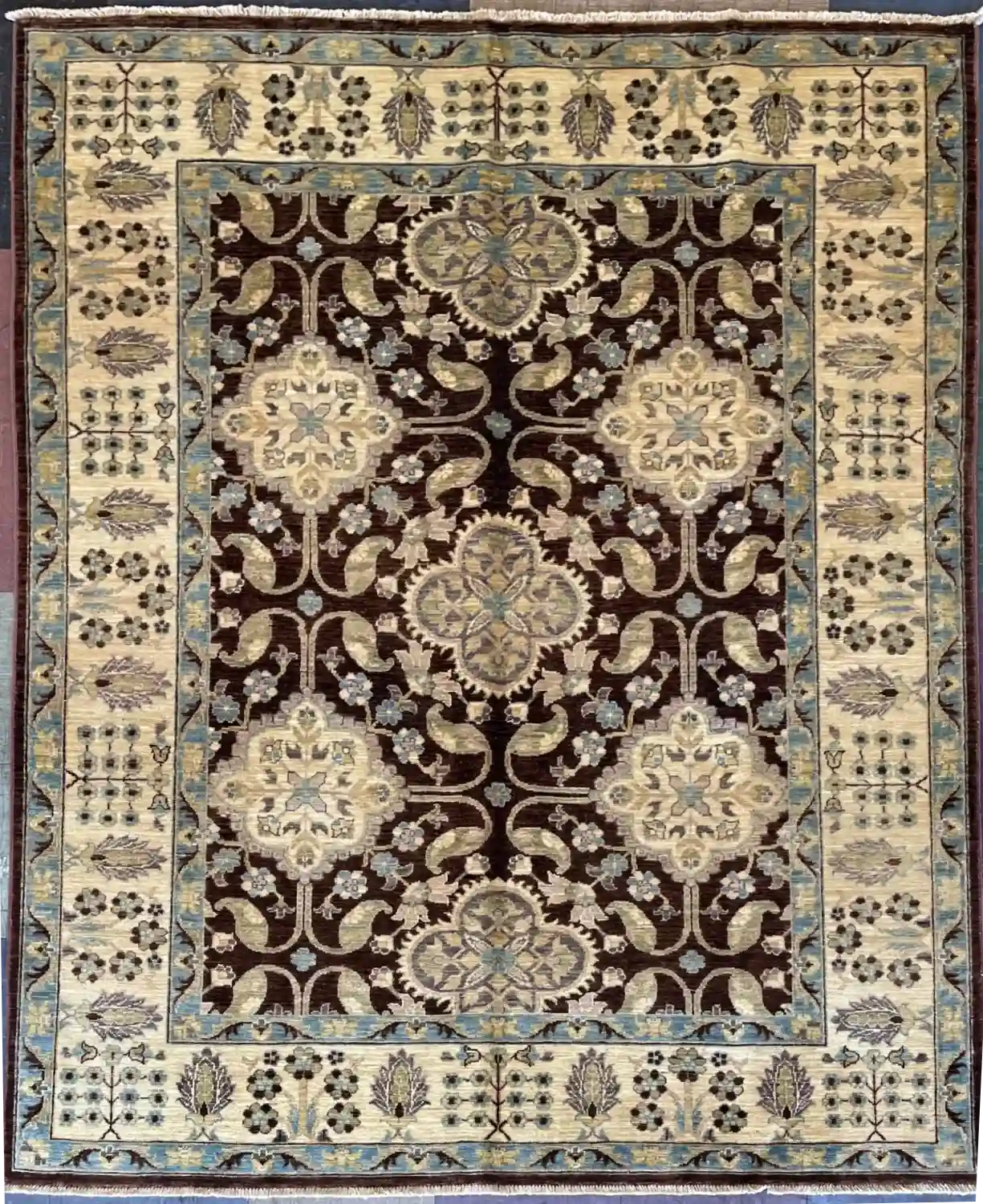 hand-knotted-chobi-wool-area-rug-5-3-x-6-9-chocolate-brown.webp | McFarlands Carpet and Rug Service Dark chocolate brown hand-knotted Chobi wool area rug 5.3' x 6.9' displaying large cream floral medallions and an elaborate cream border.