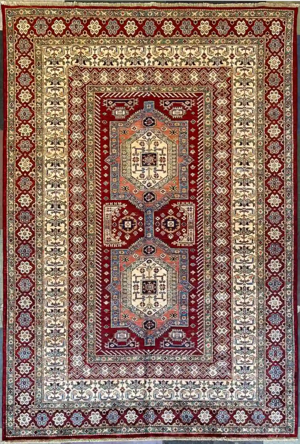 geometric-kazak-wool-rug-6x9.webp | McFarlands Carpet and Rug Service Red and ivory geometric hand-knotted Kazak wool area rug 5.11' x 8.10' showcasing a vertical double medallion tribal motif.