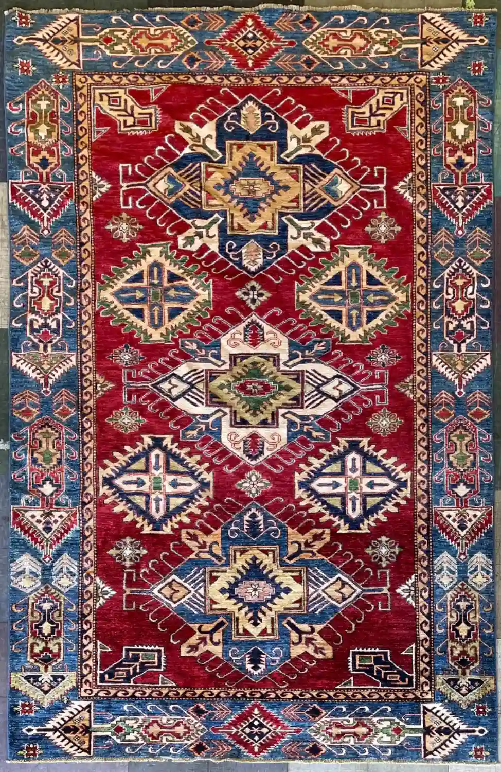 traditional-red-kazak-medallion-wool-rug-6x9.webp | McFarlands Carpet and Rug Service Traditional red Kazak hand-knotted wool area rug 6.3' x 10.4' featuring three large navy and ivory center medallions with a blue tribal border.
