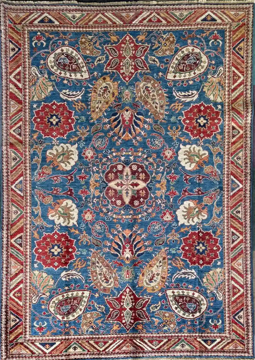 azure-blue-rust-medallion-chobi-wool-area-rug-6x9.webp | McFarlands Carpet and Rug Service Hand-knotted Chobi wool area rug 6.2' x 8.7' featuring an azure blue field, central floral medallion, rust red palmettes, and a geometric zigzag border.