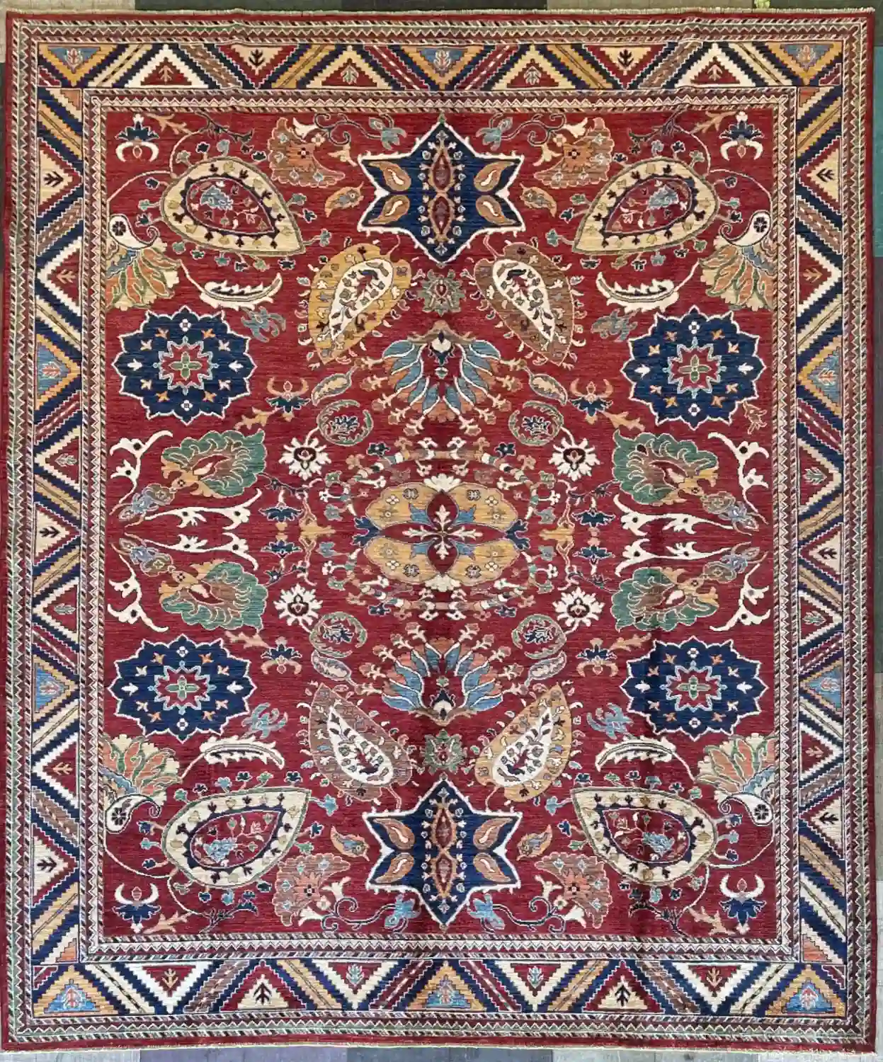hand-knotted-chobi-wool-area-rug-8-7-x-9-10-red-sku-112525-6.webp | McFarlands Carpet and Rug Service Red Hand-Knotted Chobi Wool Area Rug 8.7' x 9.10' with blue floral rosettes and geometric chevron borders.