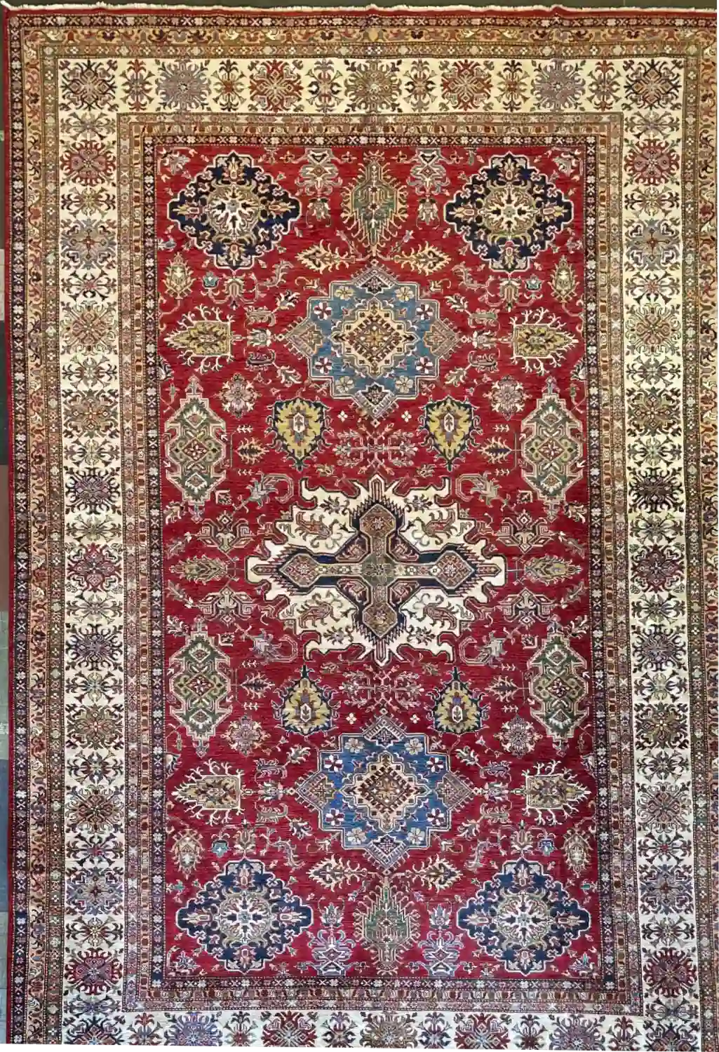 traditional-red-ivory-kazak-wool-area-rug-10x15.webp | McFarlands Carpet and Rug Service Traditional red Kazak hand-knotted wool area rug 9.10' x 15.2' featuring a central ivory cross medallion layout and a wide cream border frame.